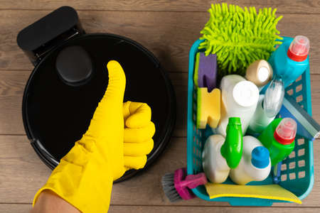 Picture of an automatic intelligent robotic vacuum cleaner  and  colorful cleaning product on the floorの写真素材