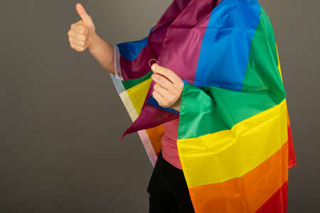 Gay man wearing pink t shirt and a rainbow flagの写真素材