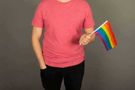Gay man wearing pink t shirt and a rainbow flagの写真素材