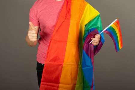 Gay man wearing pink t shirt and a rainbow flagの写真素材