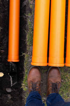 Laying down orange PVC drainage pipes into the ground