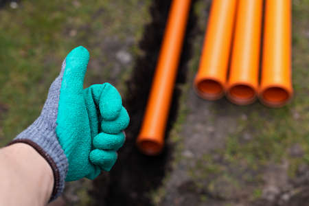 Laying down orange PVC drainage pipes into the groundの写真素材