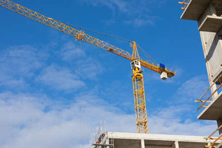 Picture of a construction crane against blue, cloudy sky