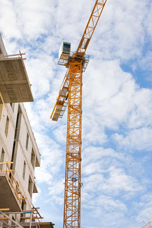 Picture of a construction crane against blue, cloudy sky