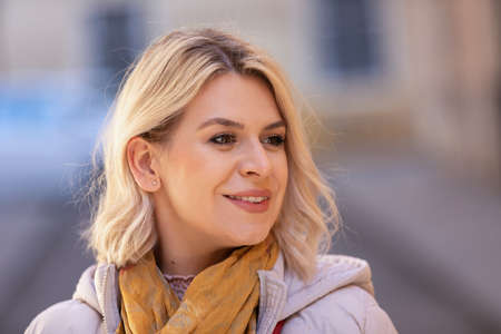 Portrait of a beautiful young woman in  jacket, posing on outdoors sidewalkの写真素材