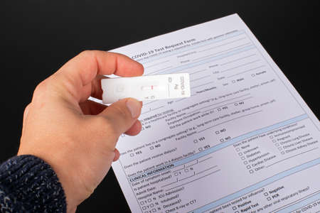 Close up picture of man hand holding coronavirus test and medical paperwork on balck backgroundの写真素材