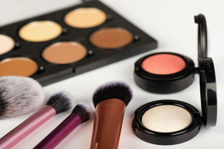 Close up picture of make up products and accessories, contour palette, brushes on white background