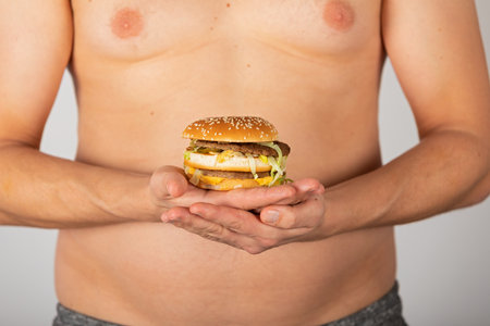 Photo of a man's hand holding a cheeseburgerの写真素材