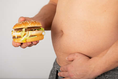 Photo of a man's hand holding a cheeseburgerの写真素材