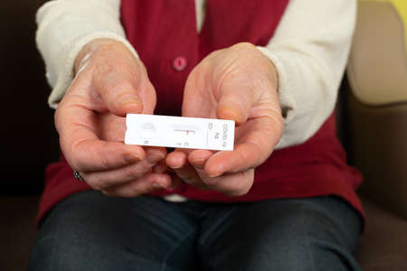 Senior hand holding a negative covid test