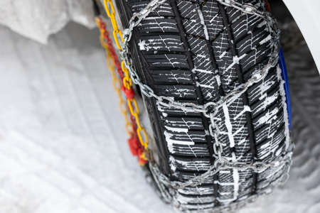 Picture of a vehicle tyre with snow chains on a frozen road