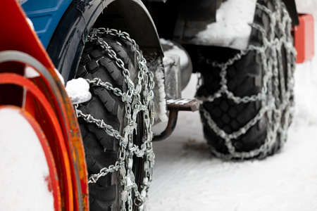 Picture of a vehicle tyre with snow chains on a frozen roadの写真素材