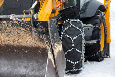 Picture of a vehicle tyre with snow chains on a frozen roadの写真素材