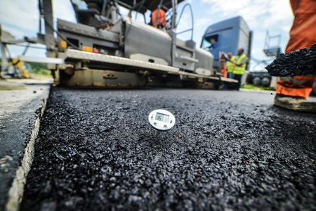 Heavy duty road building. Hot Asphalt being laid and measured for a quality check as a part of a on...