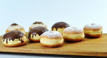 Close up. Beautifully arranged delicious doughnuts with icing, sugar, melted and sprinkled chocolate. Natural wooden background. Ideal for bakers, pastry shops or junk food, cheating on diet texts.の写真素材