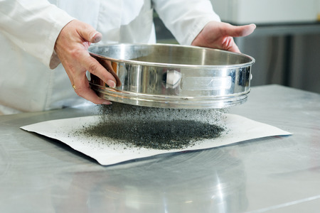 On site road testing laboratory. Placing sample of gravel into a silver container. Preparation step...