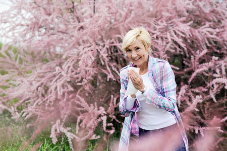 Vibrant blonde middle aged woman sneeze - spring allergiesの写真素材