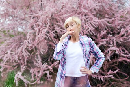 Vibrant blonde middle aged woman sneeze - spring allergiesの写真素材