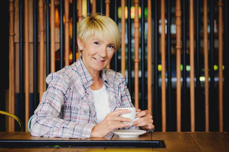 Blond woman in restaurant - having coffee の写真素材