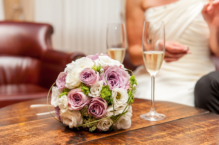 Flower bouquet and champagne glasses on wood tableの写真素材