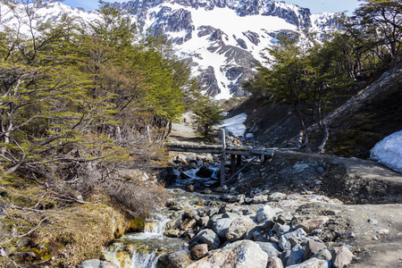 wooden bridge over a small river in the mountainsの写真素材