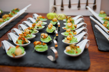 Seafood appetizers in porcelain spoons on black stone platterの写真素材