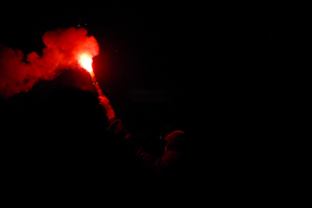 Man holding a burning red bonfire stickの写真素材