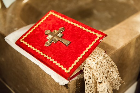 Red holly book with metal cross in churchの写真素材