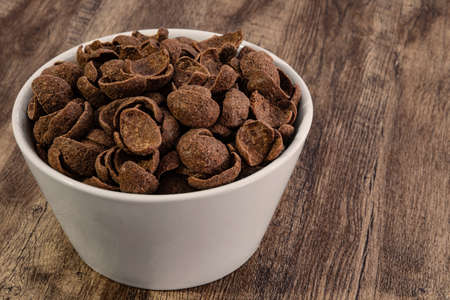 chocolate cereals in white bowl on wood background.の写真素材