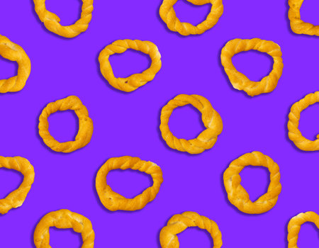 Pieces of traditional Latin American pastry called ROSQUITAS DE SAL, ROSCAS made with wheat flour. Top view of Neapolitan cookies called TARALLI. Stale salt bagels Wood table.の写真素材