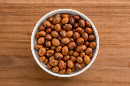 Beans in a Ceramic Bowl. These nutritious legumes are high in protein and fiber. The image is a cut out, isolated on a wood backgroundの写真素材