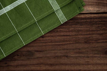Striped kitchen towel or napkin isolated on a rustic wooden table, top view. Cloth tablecloth on woody background. Composition of elements with space to assemble artisan food. Mockupの写真素材