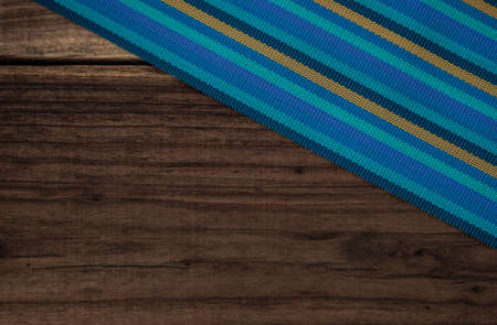 Striped kitchen towel or napkin isolated on a rustic wooden table, top view. Cloth tablecloth on woody background. Composition of elements with space to assemble artisan food. Mockupの写真素材