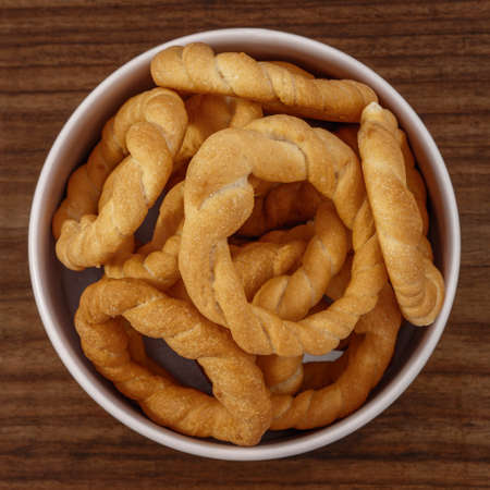 Pieces of traditional Latin American pastry called ROSQUITAS DE SAL or ROSCAS made with wheat flour. Top view of Neapolitan cookies called TARALLI. Stale salt bagels. Wood table. Ecuadorの写真素材