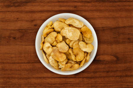 Bowl of toasted broad beans viewed from above. Highly detailed top view of toasted broad beans. Toasted broad beans tale on wooden table. Vicia fabaの写真素材