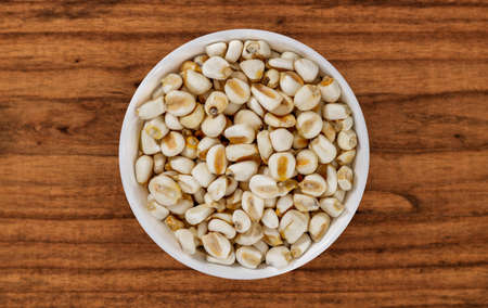 Top view of bowl with white corn for cooking on wooden table backgroundの写真素材