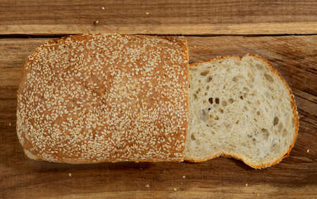 top view of a loaf of bread made from sourdough, slice of fresh bread on a wooden table. Sesame seeds on homemade bread. bakery. traditional. rustic. natural.の写真素材