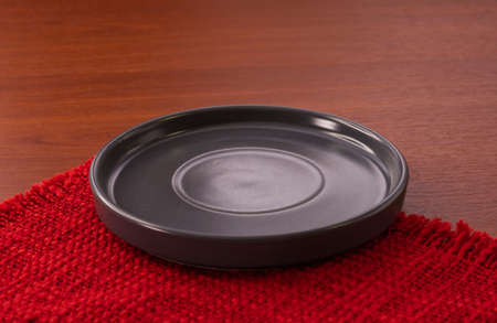 Empty plate on tablecloth on wooden table over grunge background. Table setting. Circle black dish.の写真素材