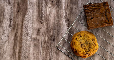 Pieces of fresh brownie and cookie on wood table background, top view. Delicious chocolate pieの写真素材