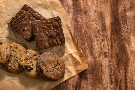 Pieces of fresh brownie and cookie on wood table background, top view. Delicious chocolate pieの写真素材