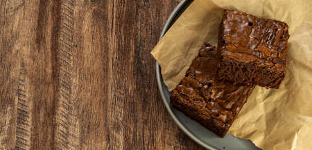 Pieces of fresh brownie on wood table background, top view. Delicious chocolate pieの写真素材