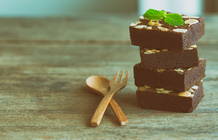 Piece of stack homemade dark chocolate brownies topping with almonds slices and mint on wood table.Bitter,sweet and fudge.Brownie is one type of chocolate cake. Vintage tone.の写真素材