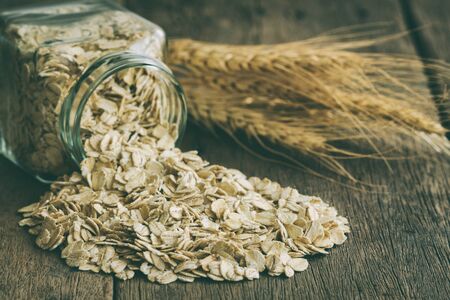 Oat flakes or oatmeal in glass bottle on rustic wood table. Rolled oat is clean food for health...