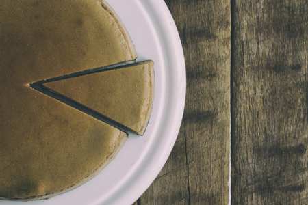Homemade chocolate cheesecake on rustic wood table.Baked chocolate cheesecake on plate. Brownie cheesecake for coffee break or tea time in cafe. Top view of triangle slice piece of chocolate cake.の写真素材