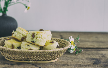 Traditional English pastry: scones. Homemade raisin scones in basket on rustic wood table. Raisin scones for afternoon tea,cream tea,high tea in devon shire or cornish style. Vintage tone concept.の写真素材