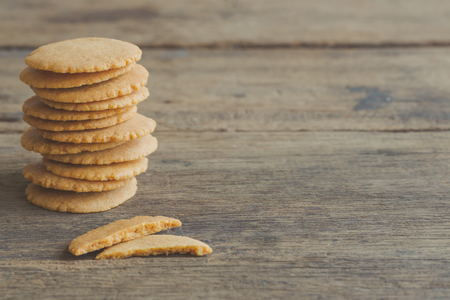 Homemade biscuits or cookies baked from multi grains so delicious, crisp and crack snack. Stack of biscuits cookies put on rustic wood table. Golden brown cookies.Thin biscuits with warm tone concept.の写真素材