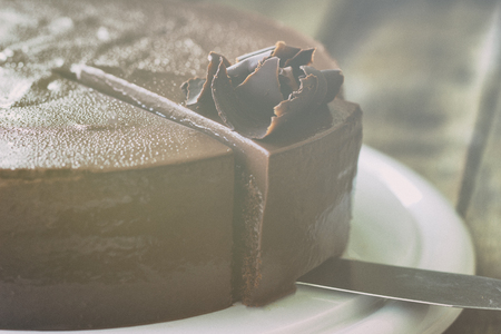 Homemade bakery: chocolate fudge cake decorated with chocolate curl. Triangle slice piece of chocolate cake on rustic wood table for cafe,meeting, coffee break or tea time and birthday party.の写真素材