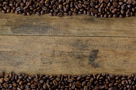 Stack of roast coffee beans. Copy space of rustic wood table line on top and below with coffee beans. Roast coffee beans on old wood table for background and wallpaper.の写真素材