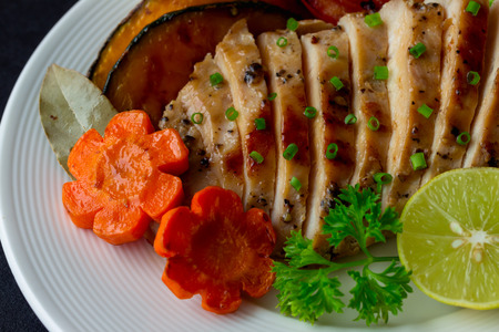Sliced chicken breast barbecue on white plate served with grilled vegetable. Delicious  chicken breast steak and salad for dinner. Homemade chicken breast barbecue on granite table for background.の写真素材