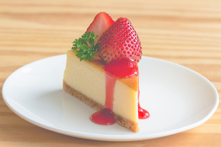 Homemade New York cheesecake on white plate decorated by strawberry,parsley and strawberry sauce. Moist and smooth classic baked cheesecake. Copy space background of delicious New York cheesecake.の写真素材
